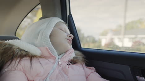 Cute-child-sleeps-while-driving-in-the-back-seat-of-a-car.