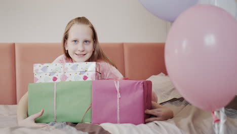 The-child-rejoices-in-birthday-gifts,-hugs-boxes-with-gifts