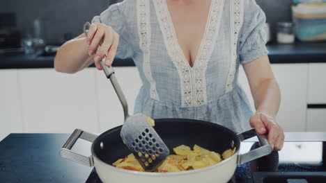 Young-housewife-frying-potatoes-in-a-trendy-modern-kitchen-at-home