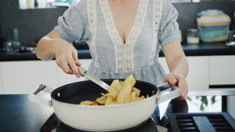 Attractive-young-woman-fries-potatoes-on-a-modern-electric-stove-with-a-built-in-extractor-fan