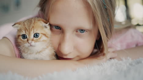 Portrait-of-a-cute-baby-with-a-ginger-kitten-looking-at-the-camera