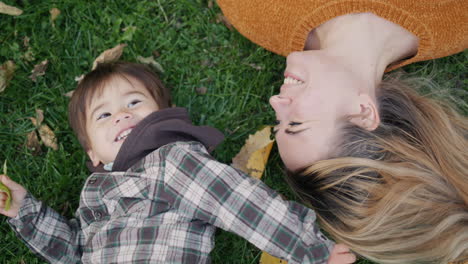 A-mother-and-child-play-together,-lie-on-the-grass-in-the-park.-Asian-kid-laughs-happily