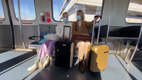 Mom-and-daughter-are-traveling-in-a-carriage-through-the-airport,-their-luggage-is-next-to-them.-Protective-masks-on-faces