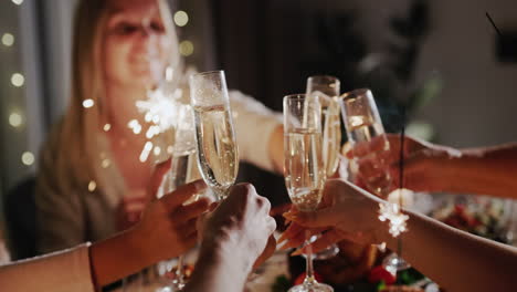 The-family-clinks-glasses-over-the-festive-table,-holds-sparklers-in-their-hands