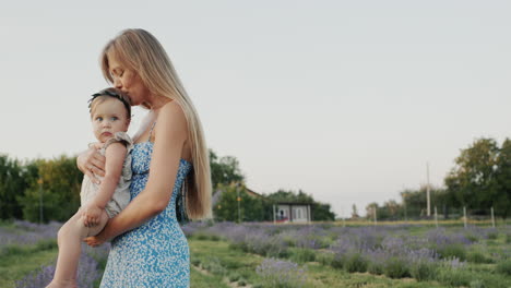 Gentle-loving-mother-with-her-daughter.-Standing-against-the-backdrop-of-lavender,-in-the-distance-their-house