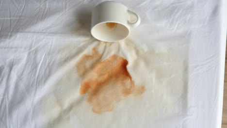 Cup-of-coffee-spilled-on-bed-top-view-,