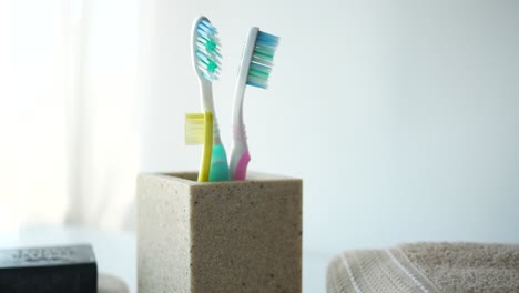 Ful-toothbrushes-in-white-mug-against-a-wall