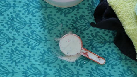 Washing-powder-in-plastic-spoon-on-blue-background-,