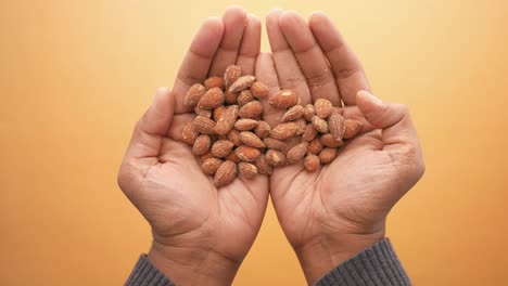 Close-up-of-almond-nuts-on-mans-hand