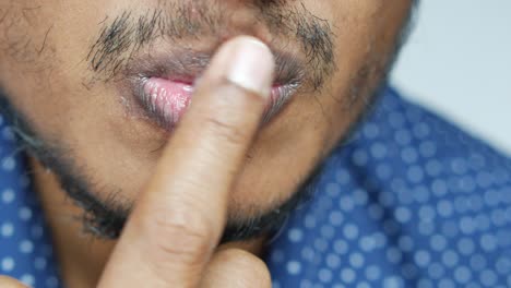 Close-up-of-young-man-applying-petroleum-jelly-on-lip