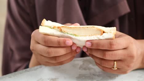 Women-eating-a-chicken-egg-sandwich