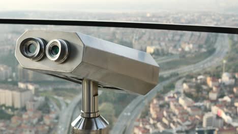 Coin-operated-binoculars-looking-out-over-city-buildings