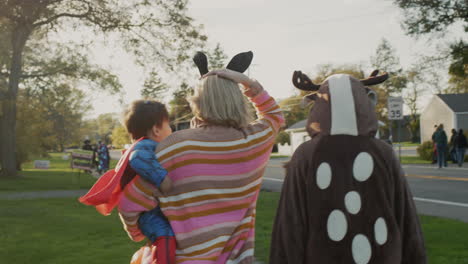 Woman-with-two-children-in-carnival-costumes-in-honor-of-Halloween.-Walking-down-the-street-of-a-small-American-town