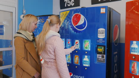 Lockport,-NY,-USA,-October-2021:-Mom-with-child-buys-a-carbonated-drink-from-the-vending-machine.