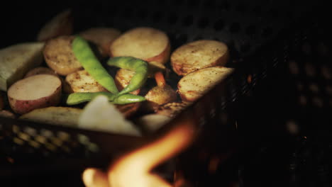 Potatoes-with-asparagus-are-fried-in-a-frying-pan-over-an-open-fire.-Delicious-picnic-food
