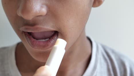 Young-man-applying-moisturising-lip-balm-on-lips