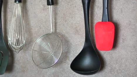 Kitchen-utensils-hanging-on-gray-background
