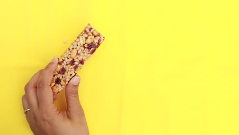 Holding-a-oat-protein-bar-on-yellow-background