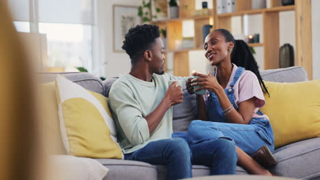 Tea,-chatting-and-a-happy-black-couple-on-a-sofa