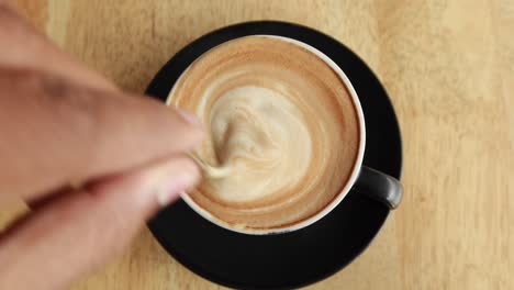 Person-hand-stirring-coffee-with-spoon