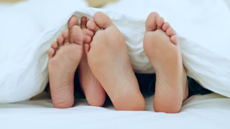 Couple,-feet-and-relax-in-bed-together-on-holiday