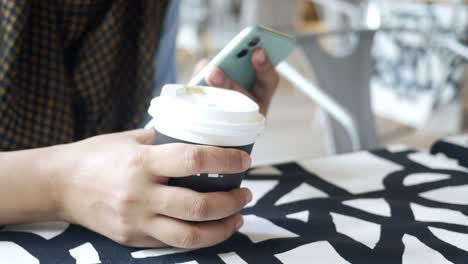 Women-hand-holding-smart-phone-and-paper-coffee-cup-,