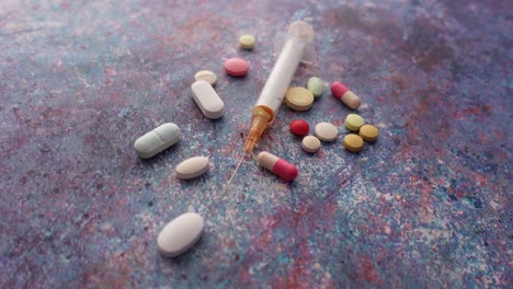 Syringe-and-pills-on-dark-background,-close-up