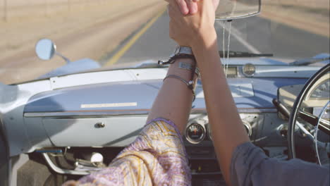 beautiful-Woman-enjoying-ride-in-convertible-vintage-car-on-road-trip-with-outstretched-arms