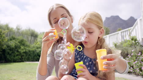 Mutter-Und-Tochter-Blasen-Seifenblasen-Im-Hof,-Glückliches-Familienhaus
