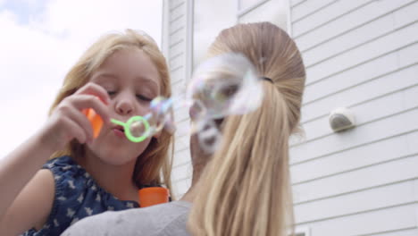Mother-and-Daughter-blowing-bubbles-in-the-yard-happy-family-home