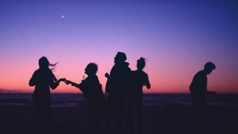 Group-of-friends-dancing-on-the-beach-at-dusk