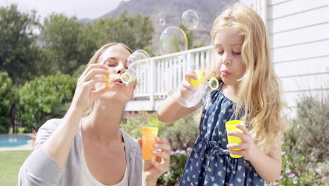 Mother-and-Daughter-blowing-bubbles-in-the-yard-happy-family-home