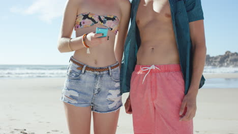 Cropped-shot-Caucasian-couple-using-smart-phone-on-the-beach