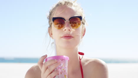 Close-up-portrait-of-beautiful-young-teenage-girl-drinking-water-from-pink-plastic-cup-on-tropical-beach-slow-motion