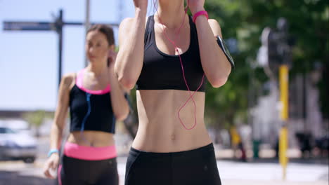 Close-up-crop-of-torso-Two-running-women-Fitness-athletic-friends-jogging-in-the-urban-city