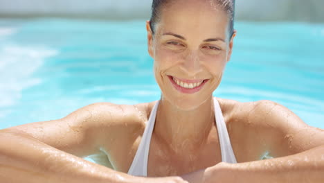 Attractive-woman-swimming-to-surface-edge-of-pool-and-smiling