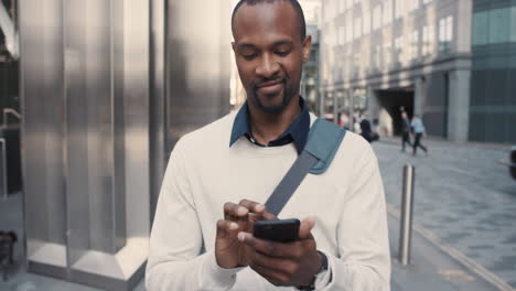 Hombre-De-Negocios-Afroamericano-Caminando-Por-La-Ciudad-Usando-Un-Teléfono-Inteligente
