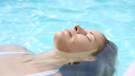Attractive-woman-floating-in-swimming-pool