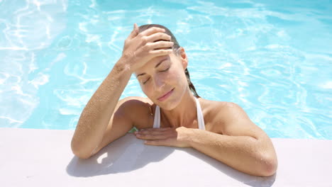 Attractive-woman-relaxing-at-edge-of-swimming-pool