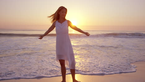Free-happy-woman-spinning-arms-outstretched-enjoying-natural--lifestyle-dancing-on-beach-at-sunset-slow-motion-RED-DRAGON