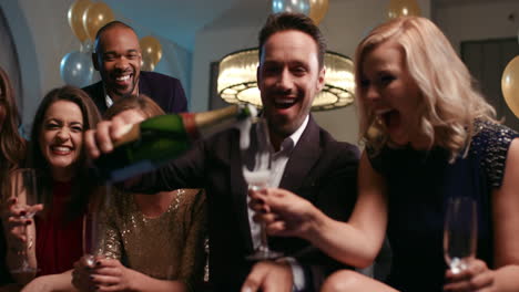 Friends-holding-up-champagne-flutes-together-in-a-toast-at-party