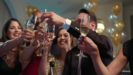 Friends-holding-up-champagne-flutes-together-in-a-toast-at-party