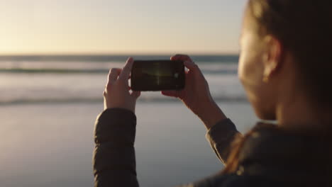 close-up-of-young-woman-taking-photo-of-beautiful-beach-sunset-using-smartphone-camera-technology-enjoying-calm-summer-vacation-lifestyle