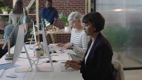 mature-mixed-race-business-woman-using-computer-in-diverse-modern-office-workspace-colleagues-working-on-corporate-project-creative-multi-ethnic-team