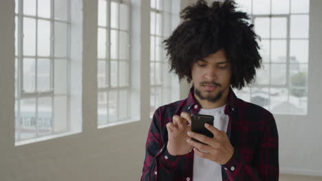 portrait-of-young-mixed-race-man-student-using-smartphone-texting-browsing-online-social-media-messaging-on-mobile-phone-technology-in-apartment