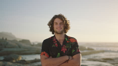 portrait-of-relaxed-young-man-with-arms-crossed-smiling-at-beach-wearing-hawaiian-shirt