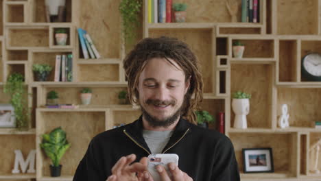 portrait-of-young-attractive-man-with-dreadlocks-browsing-social-media-using-smarphone-smiling-cheerful