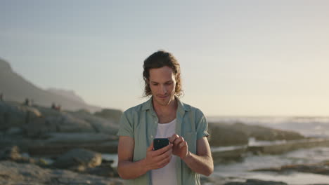 Porträt-Eines-Mannes,-Der-Bei-Sonnenuntergang-Am-Strand-SMS-Schreibt