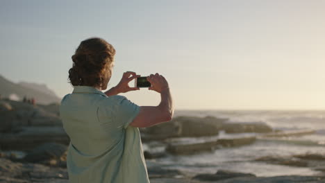 portrait-of-handsome-man-taking-photo-at-sunset-by-beach