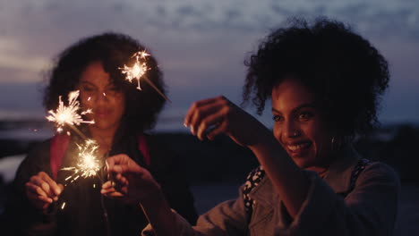 portrait-of-beautiful-mixed-race-sisters-celebrating-new-years-eve-holding-sparklers-twins-dancing-on-beach-enjoying-evening-party